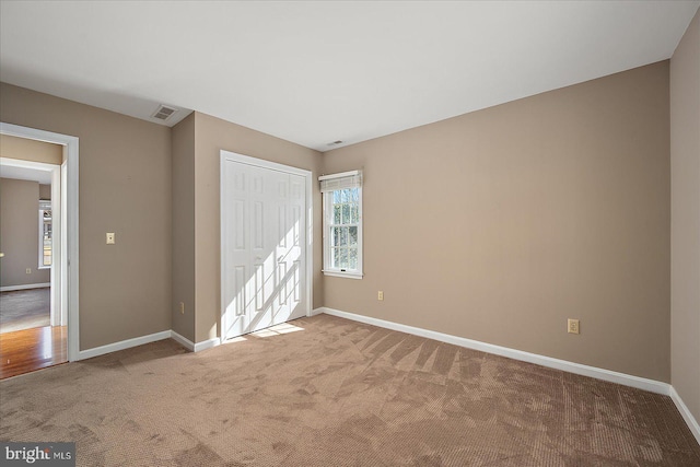 unfurnished bedroom with a closet, visible vents, baseboards, and carpet