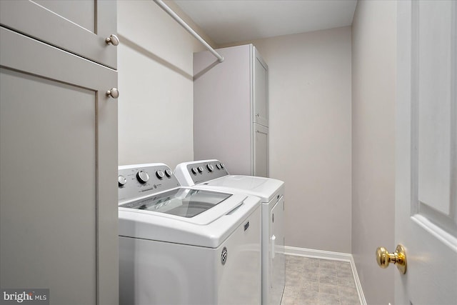 washroom with cabinet space, baseboards, and separate washer and dryer