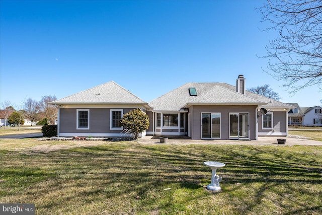 rear view of property with a lawn, a chimney, roof with shingles, and a sunroom