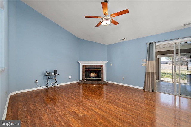 unfurnished living room with visible vents, a brick fireplace, ceiling fan, and wood finished floors