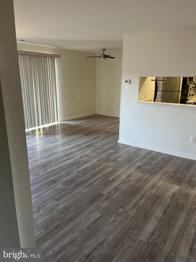 spare room with ceiling fan, dark wood finished floors, and baseboards