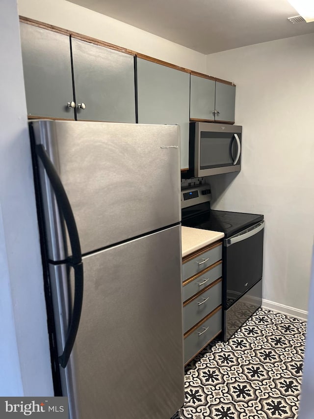 kitchen with light countertops, visible vents, gray cabinetry, appliances with stainless steel finishes, and baseboards