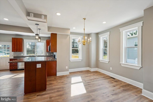 kitchen with a wealth of natural light, baseboards, brown cabinetry, and wood finished floors