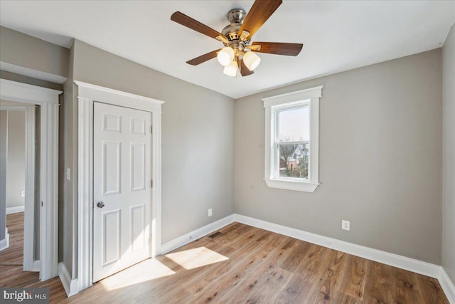 unfurnished bedroom featuring ceiling fan, light wood finished floors, and baseboards