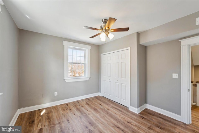 unfurnished bedroom with ceiling fan, baseboards, a closet, and wood finished floors