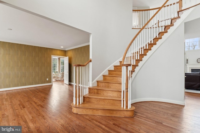 staircase with plenty of natural light, crown molding, baseboards, and wood finished floors