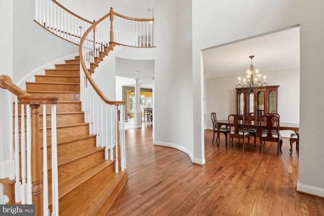 foyer entrance with stairs, an inviting chandelier, crown molding, and wood finished floors