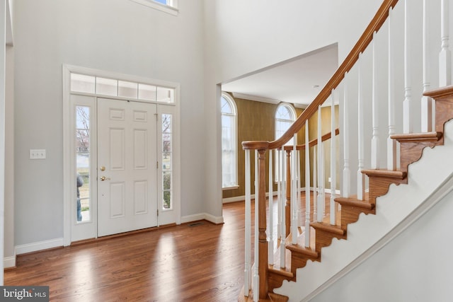 foyer entrance featuring stairway, baseboards, a high ceiling, and wood finished floors