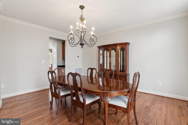 dining area with light wood-style flooring, baseboards, a chandelier, and crown molding