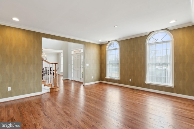 empty room with wood finished floors, baseboards, stairs, crown molding, and a notable chandelier