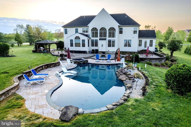 back of property with a gazebo, a patio, a lawn, and an outdoor fire pit