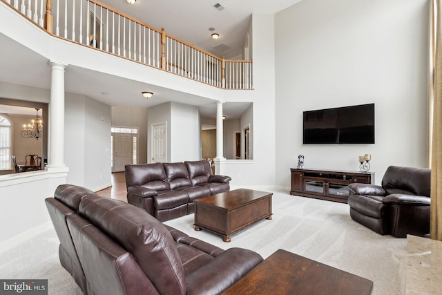 carpeted living area with a high ceiling, decorative columns, and baseboards