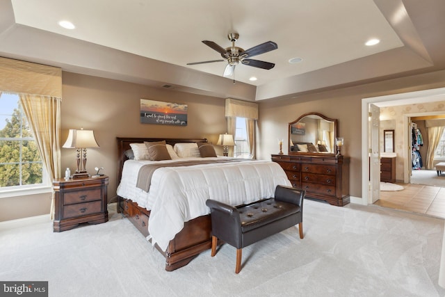 bedroom featuring a tray ceiling, recessed lighting, baseboards, and light carpet