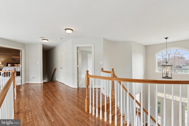 hall featuring an upstairs landing, baseboards, and hardwood / wood-style floors