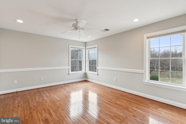 empty room with visible vents, a healthy amount of sunlight, and wood-type flooring