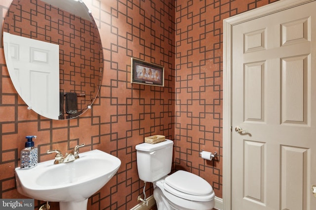 bathroom featuring a sink, toilet, and tile walls