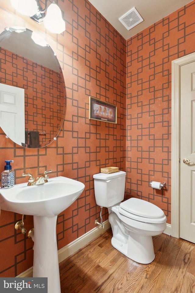 bathroom featuring toilet, wood finished floors, visible vents, and baseboards