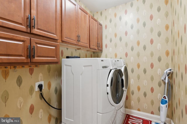 laundry area featuring wallpapered walls, washer and dryer, cabinet space, and baseboards