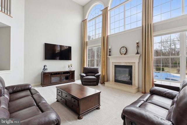 living area featuring a high ceiling, carpet flooring, plenty of natural light, and a high end fireplace