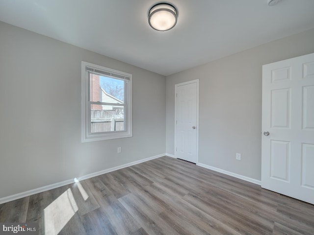 spare room featuring baseboards and wood finished floors