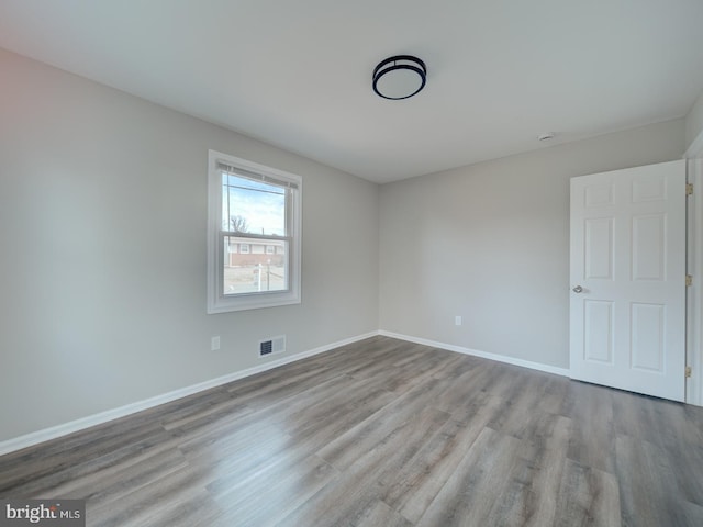 unfurnished room with visible vents, baseboards, and wood finished floors