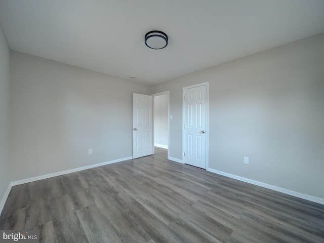 unfurnished bedroom featuring baseboards, dark wood finished floors, and a closet