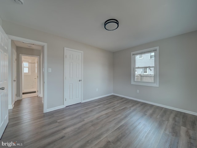 unfurnished bedroom featuring multiple windows, baseboards, and wood finished floors