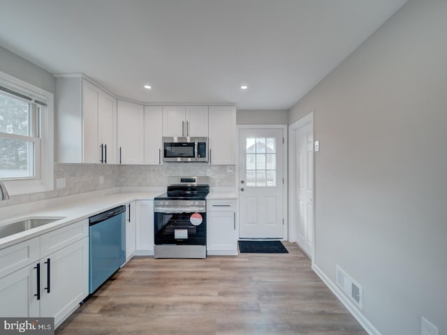 kitchen featuring tasteful backsplash, white cabinetry, visible vents, and stainless steel appliances