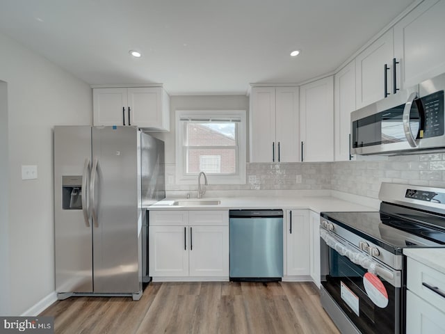 kitchen featuring light wood finished floors, white cabinetry, appliances with stainless steel finishes, and a sink