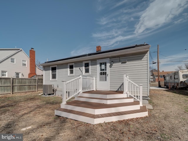 back of property with fence, a chimney, and central air condition unit