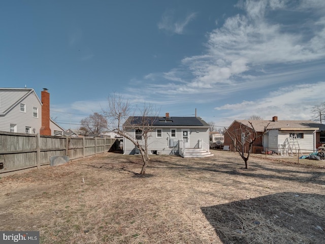 back of property with a fenced backyard and solar panels