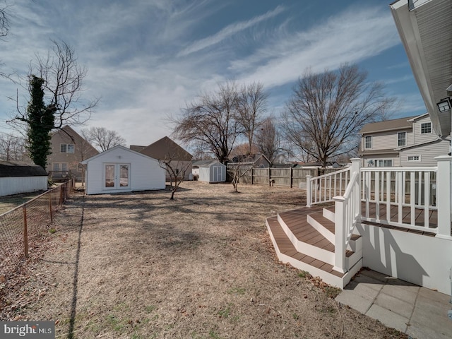 view of yard with a residential view, a fenced backyard, an outdoor structure, and a deck