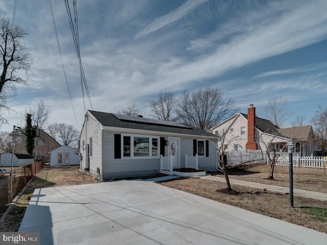 view of front of property featuring roof with shingles, fence, and solar panels