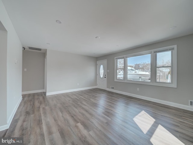 unfurnished living room featuring wood finished floors, visible vents, and baseboards