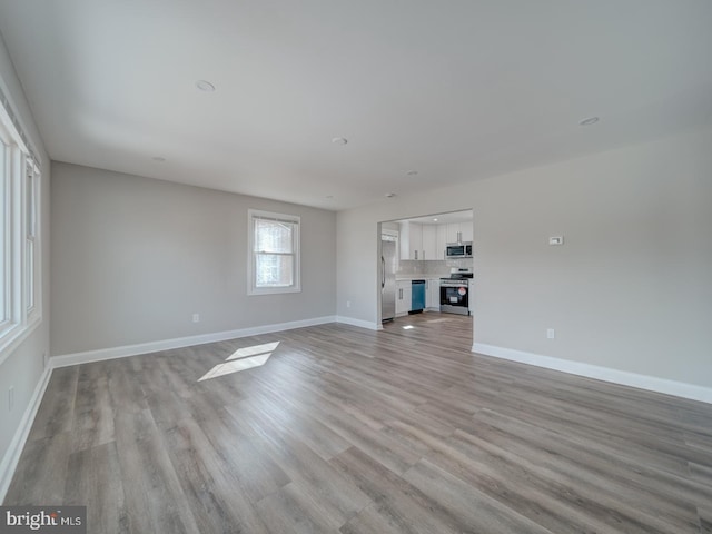 unfurnished living room featuring light wood-type flooring and baseboards