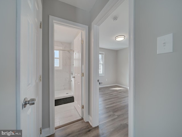 hallway featuring wood finished floors, visible vents, and baseboards