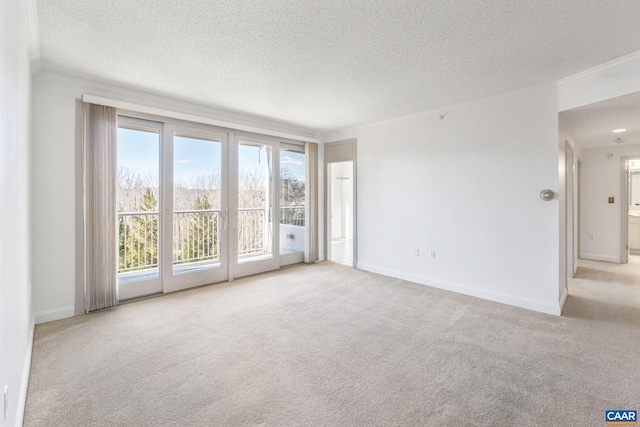 carpeted spare room featuring a textured ceiling, ornamental molding, and baseboards