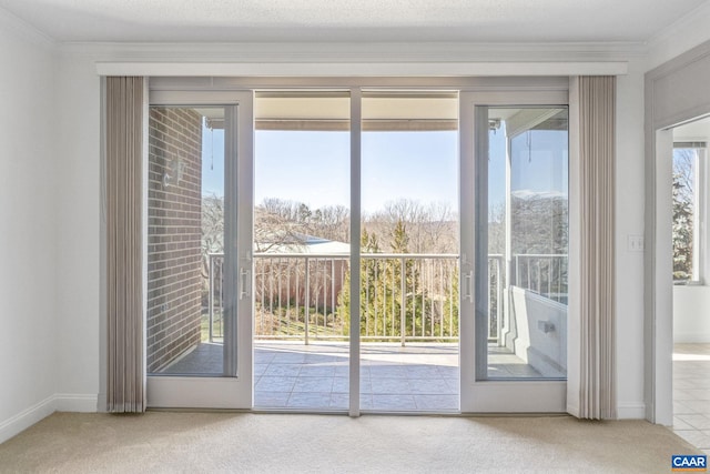 doorway with ornamental molding, carpet flooring, and baseboards