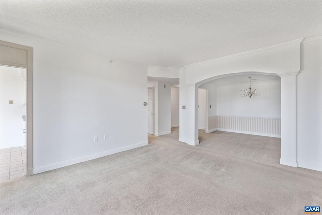 unfurnished room featuring carpet, arched walkways, ornamental molding, a textured ceiling, and a chandelier