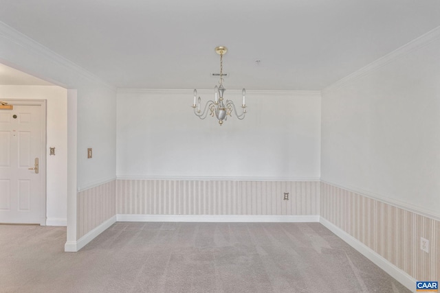 empty room with a wainscoted wall, a chandelier, carpet flooring, and ornamental molding