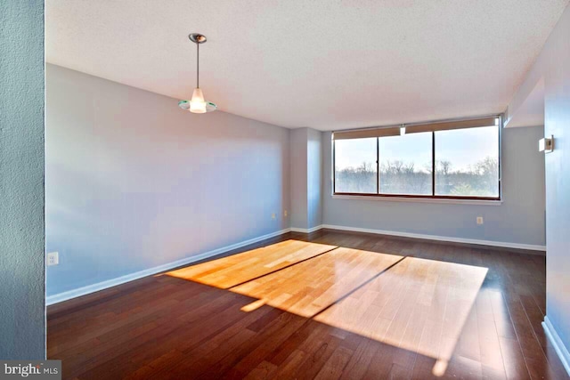 unfurnished room with a textured ceiling, wood-type flooring, and baseboards