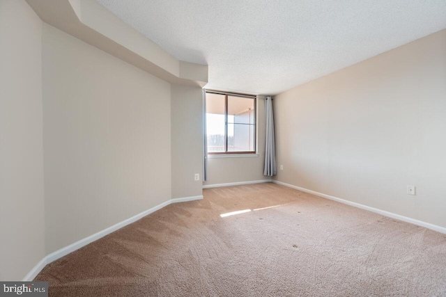 carpeted empty room featuring a textured ceiling and baseboards