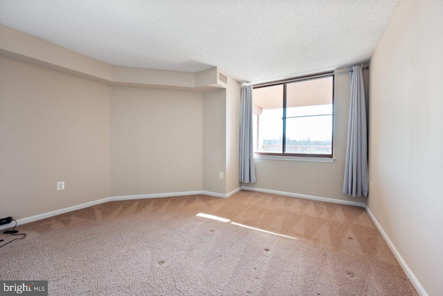 carpeted spare room featuring a textured ceiling and baseboards