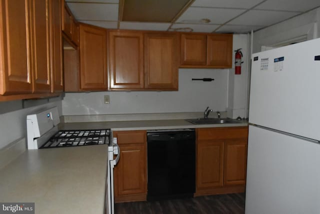 kitchen featuring brown cabinetry, white appliances, light countertops, and a sink