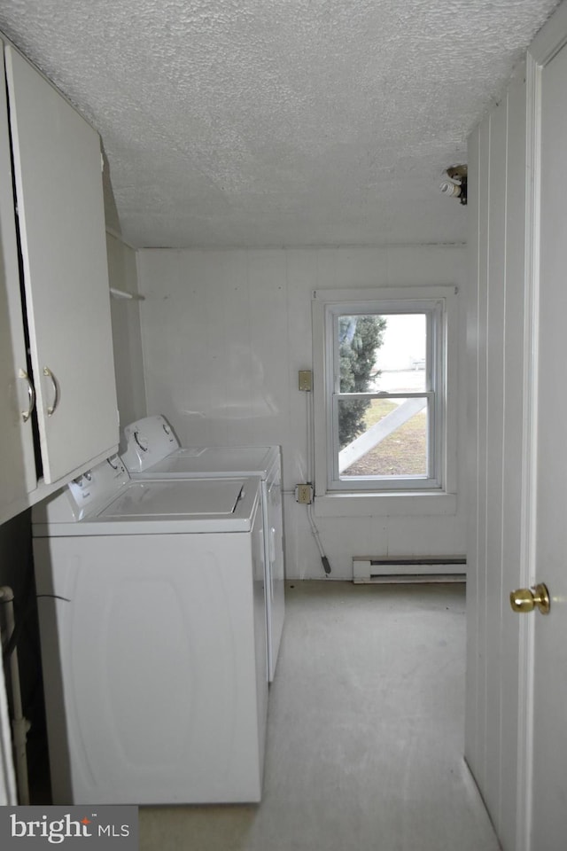 washroom featuring a textured ceiling, baseboard heating, washing machine and clothes dryer, and cabinet space