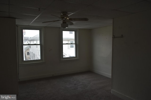 spare room featuring carpet floors, ceiling fan, baseboards, and a drop ceiling