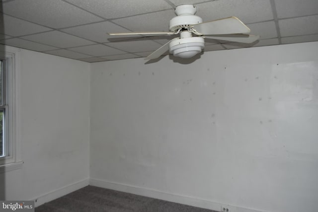 carpeted spare room featuring a paneled ceiling, ceiling fan, and baseboards