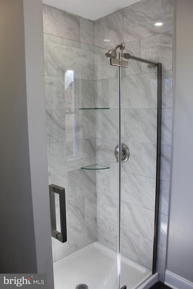 full bath featuring a shower stall and baseboards