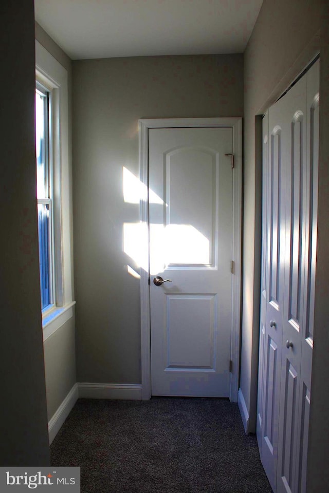 doorway with carpet floors and baseboards
