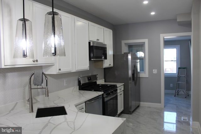 kitchen with stainless steel appliances, white cabinets, a sink, and light stone counters